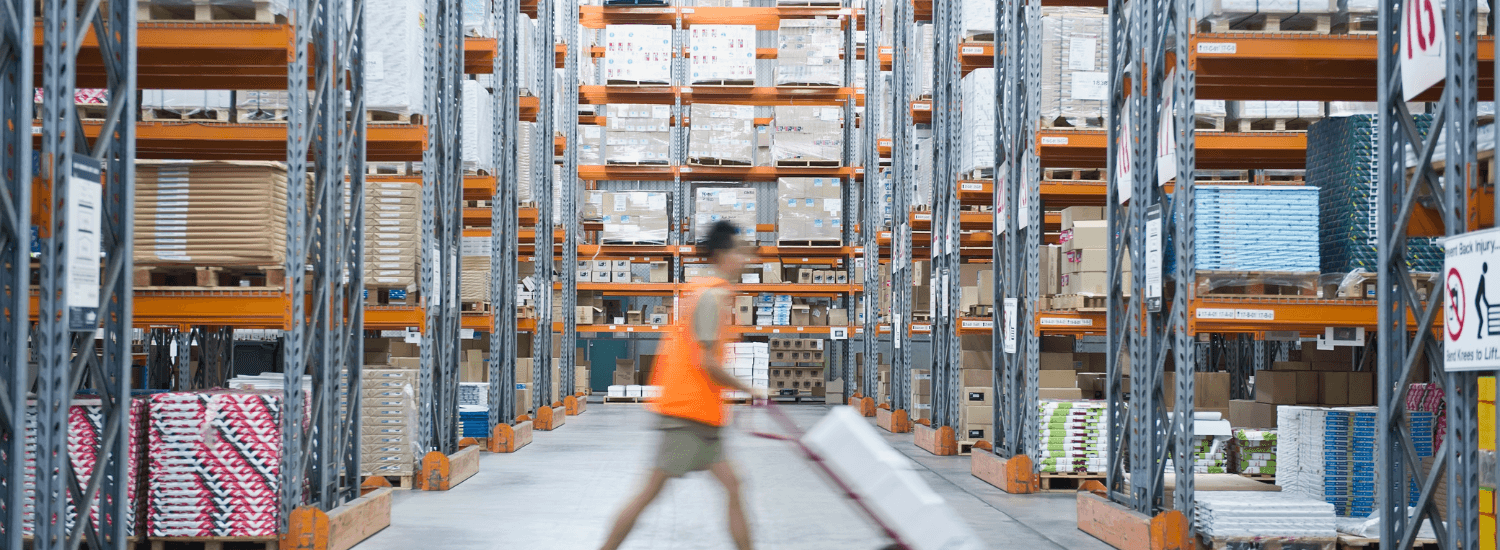 Worker pushing hand truck in warehouse